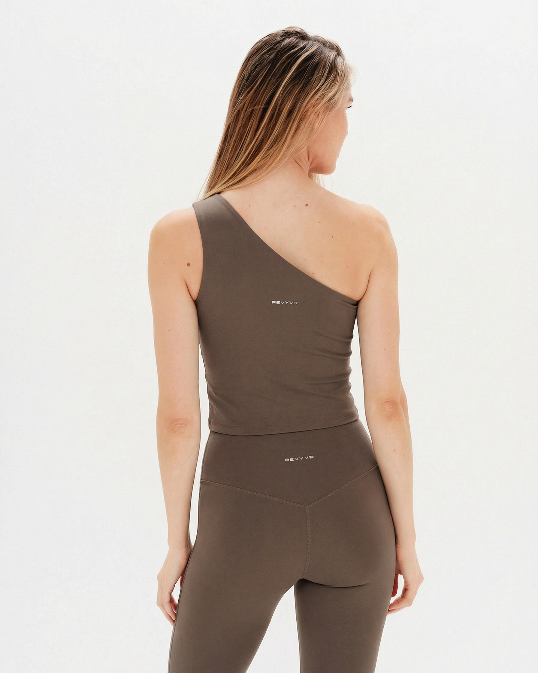 Woman wearing a brown tank top and leggings on a white background