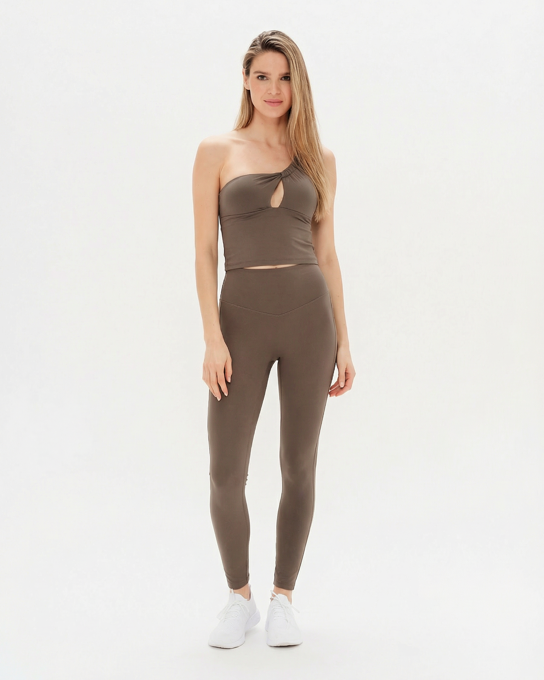 Woman wearing a brown one-shoulder top and leggings on a white background