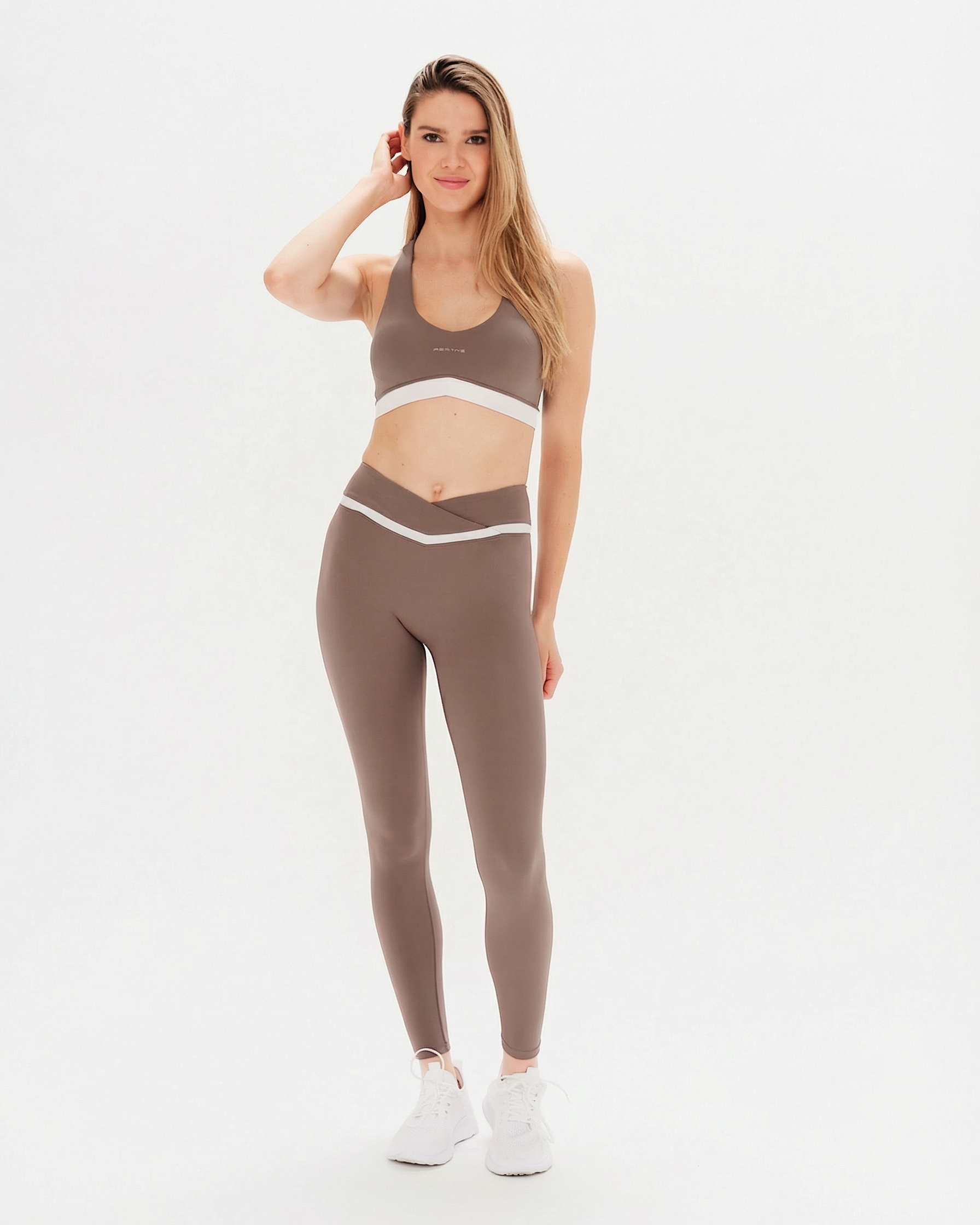 Woman wearing a brown sports bra and leggings set on a white background