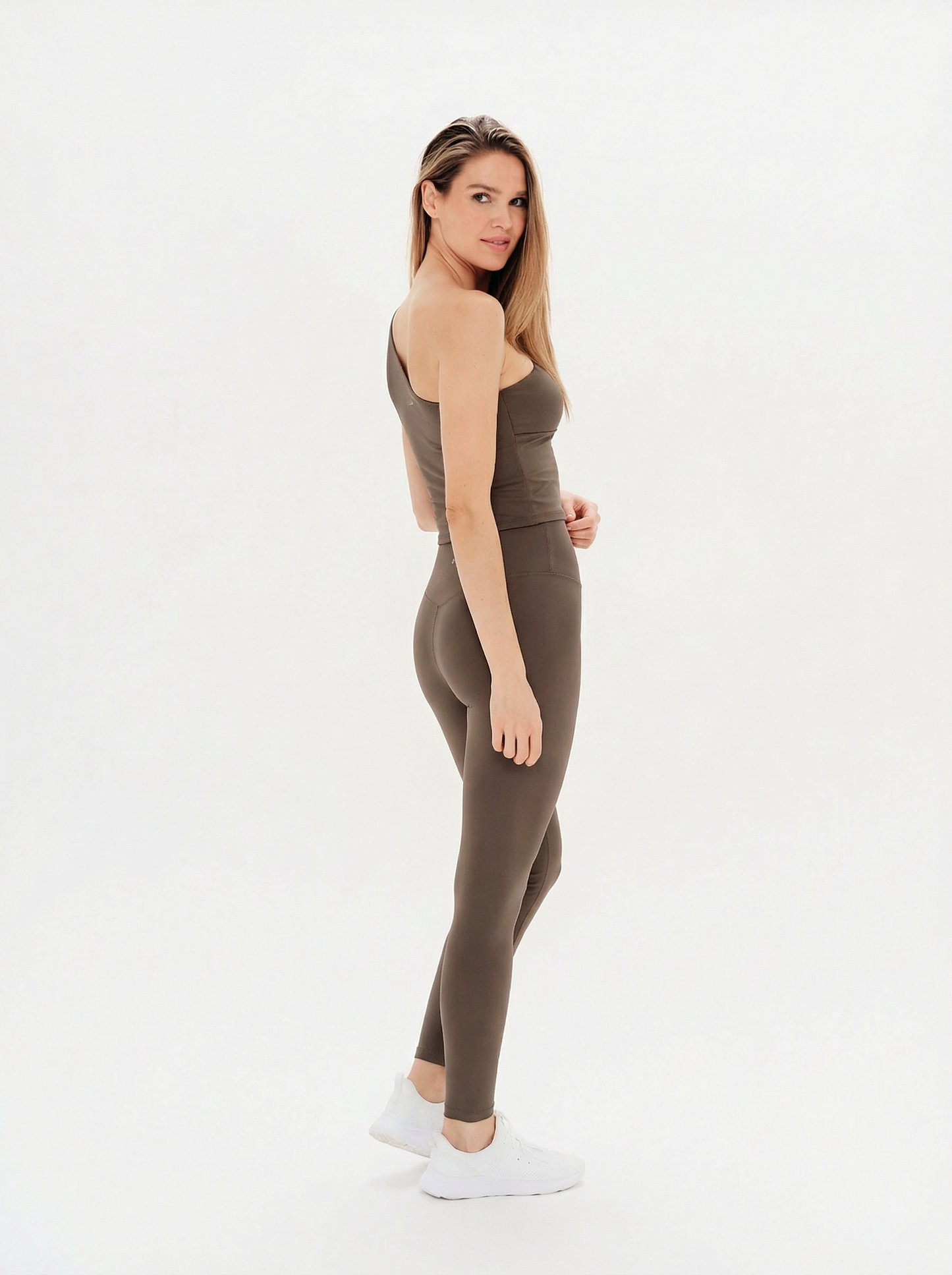 Woman wearing a brown sleeveless top and leggings on a white background