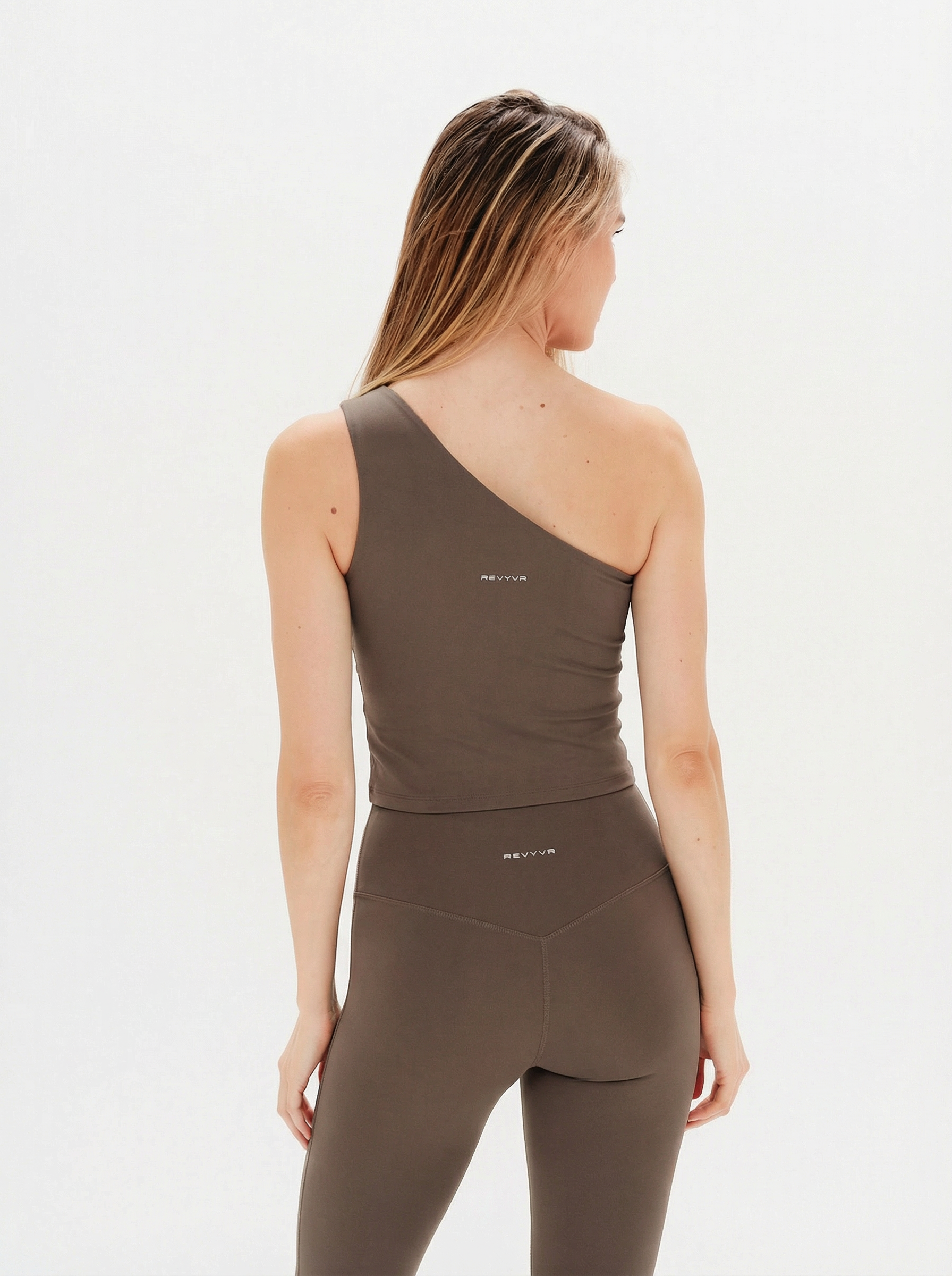 Woman wearing a brown tank top and leggings on a white background