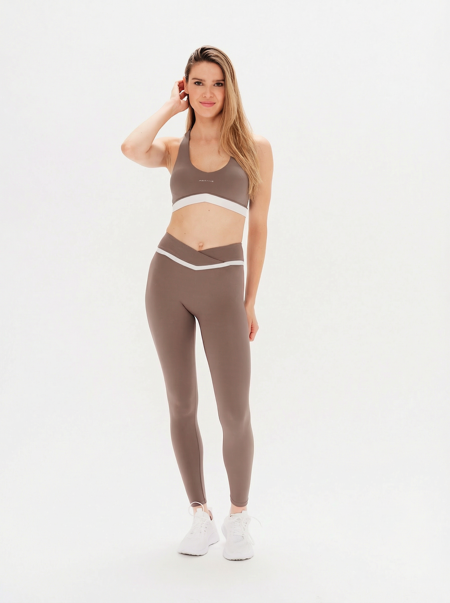 Woman wearing a brown sports bra and leggings set on a white background