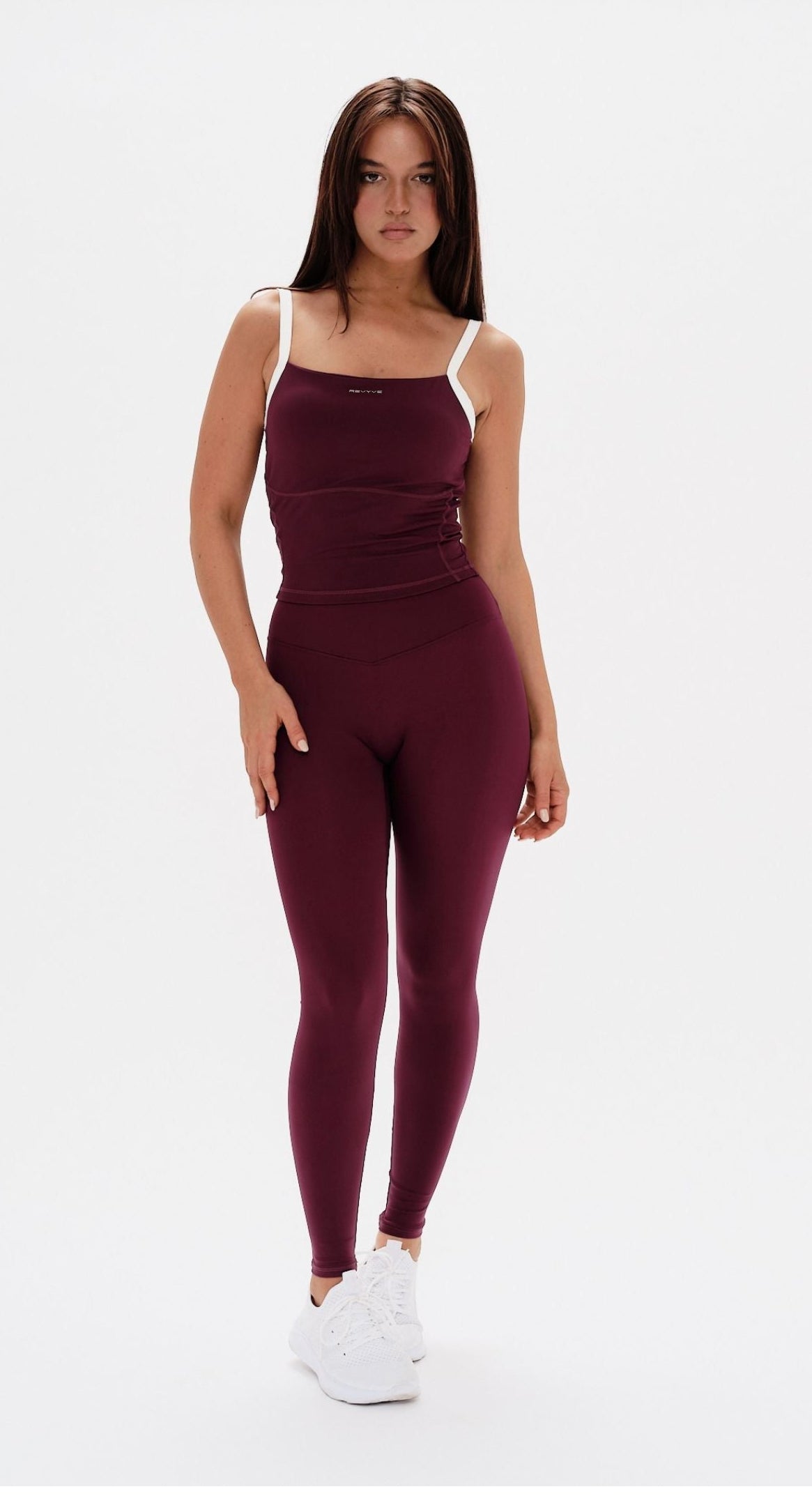 Woman wearing a burgundy athletic outfit on a white background